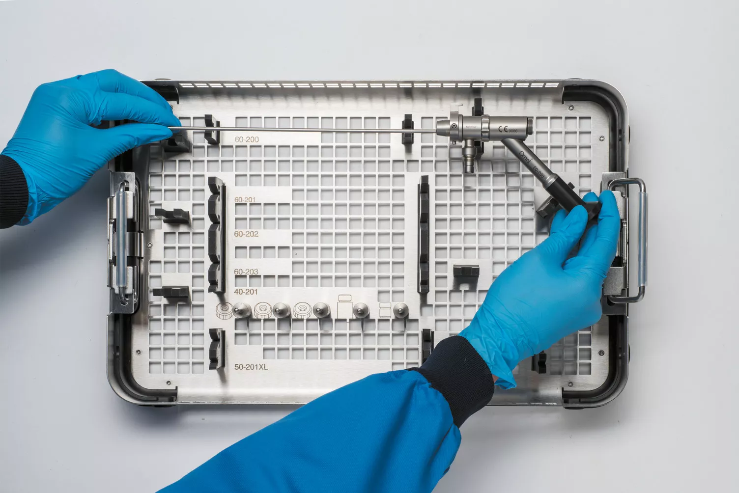 Behandskede hænder arbejder på en medicinsk bakke på et bord.