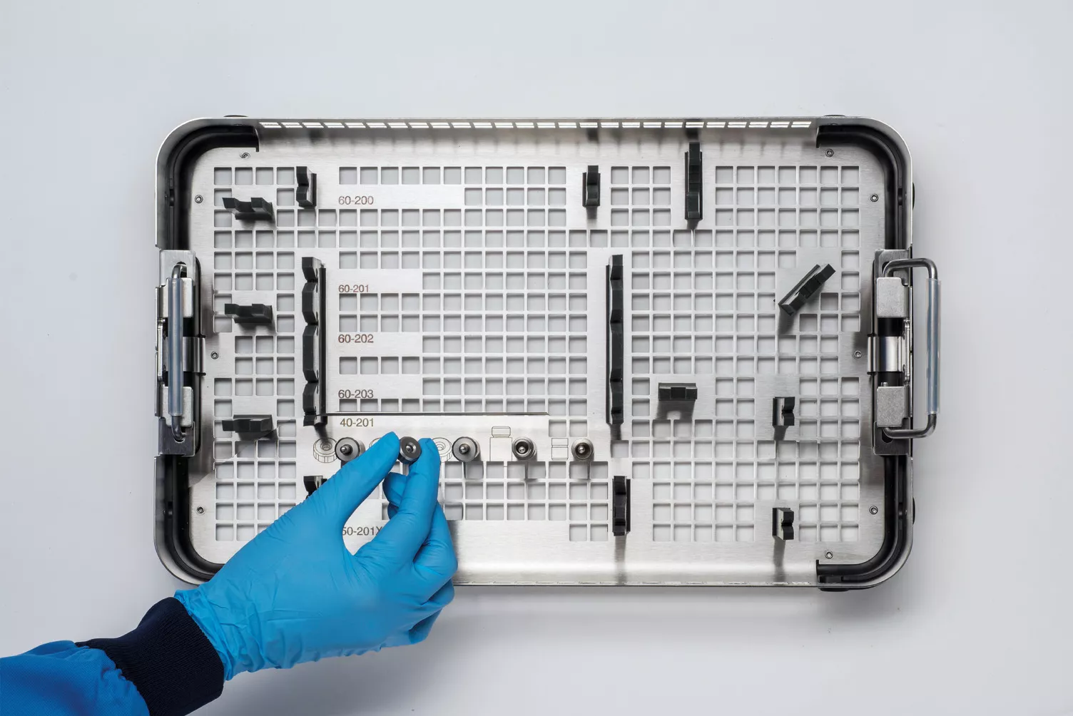 Behandsket hånd arbejder på en medicinsk bakke på et bord.